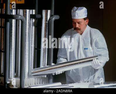 MODEL RELEASED. Cylinders of aluminium. Worker holding a cylinder of aluminium that has just been manufactured in an aluminium processing plant. Alumi Stock Photo