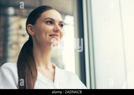 Beautiful woman in bathrobe smiling and looking into the distance Stock Photo