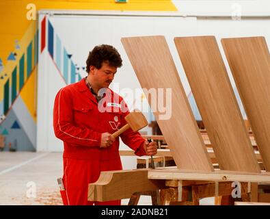 Constructing stairs. Carpenter uses a mallet and chisel while building a wooden staircase. Stock Photo