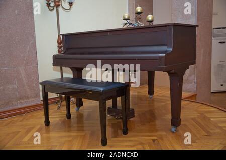 Old wooden piano keys on wooden musical instrument in front view . Big brown wooden piano close up in room .