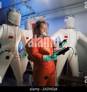 Protective suit manufacture. Technician checking gas pressure levels in Mururoa radiation protection suits. The suit is cooled by a flow of gas, which Stock Photo