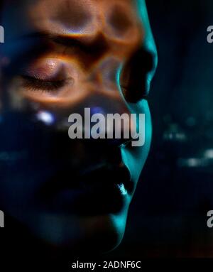 Mind reading. Conceptual image of a woman's thoughts being scanned represented by light over her face. Stock Photo