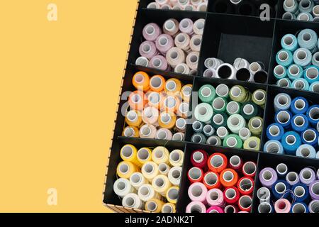 Set of color sewing threads in cardboard compartment box on yellow background Stock Photo