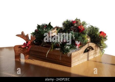 Wooden reindeer by tray of Christmas ornaments and decorations. White background. Stock Photo