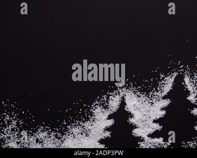 Christmas trees, wintertime. Two white Pine trees silhouette, form with snow made of rice around isolated on Black background. Stock Photo