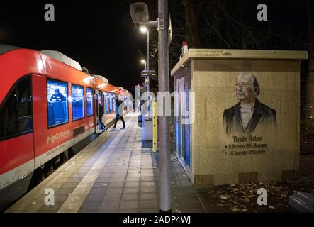 Neuruppin, Germany. 28th Nov, 2019. The wall of a small building on the Rheinsberger Tor railway station in Fontane town in the Ostprignitz-Ruppin district shows the graffiti of the poet Theodor Fontane and his date of birth and death. The Prignitz-Express in the direction of Berlin is ready for departure on platform 1. Credit: Soeren Stache/dpa-Zentralbild/ZB/dpa/Alamy Live News Stock Photo