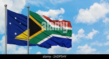 Tokelau and South Africa flag waving in the wind against white cloudy blue sky together. Diplomacy concept, international relations. Stock Photo