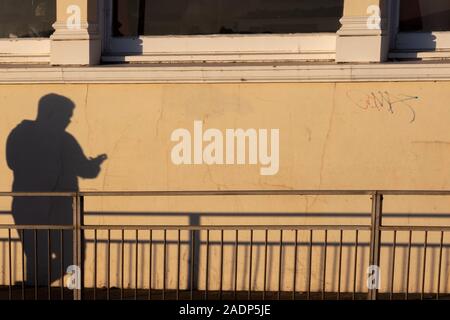guys shadow on the wall texting Stock Photo