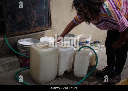 Caracas, Miranda, Venezuela. 29th Nov, 2019. Aura filling the water contaners with the water from Aura's sister's house.Aura Graciela Sarmiento, age 56, and her husband Jose Alberto Abreu, age 62, have not had running water at their house in 4 years. Aura works in a store selling office furniture, and Jose is a mechanic. They live in the neighborhood of Altos de Lidice in Caracas Venezuela. Altos de Lidice is a historic Chavista neighborhood. However, Aura is pro-Opposition, and has never supported the Chavez regime even though she has lived in this pro-Chavez/Maduro barrio her whole life Stock Photo
