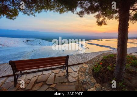 Bench overlooking the Travertine pools and terraces on Pamukkale, Turkey in sunset time Stock Photo