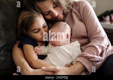 Loving mother embracing 4 yr old daughter and newborn baby Stock Photo