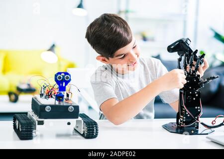 Cheerful schoolboy making experiments with his robotic device Stock Photo
