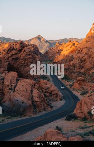 Car driving on a road trough a valley surrounded by red rocks Stock Photo