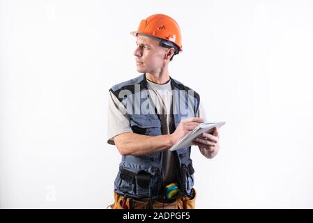 Builder with a notepad. In a helmet and a robe. Writes data. Stock Photo