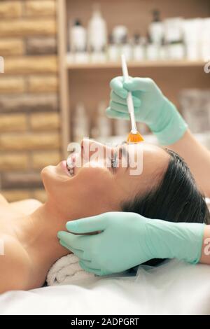 Face of excited woman lying and having her face cleaned Stock Photo