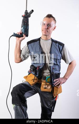The builder holds a drill up. In construction unloading, and safety glasses. Stock Photo