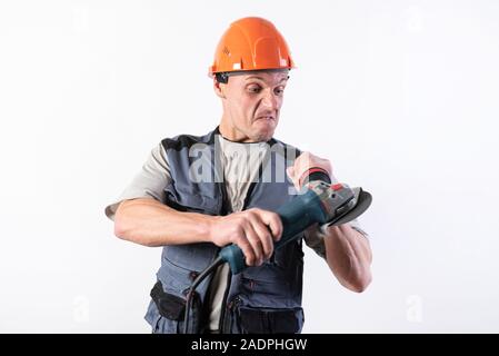 Builder with angle grinder, in a helmet, with a funny expression on his face. Stock Photo