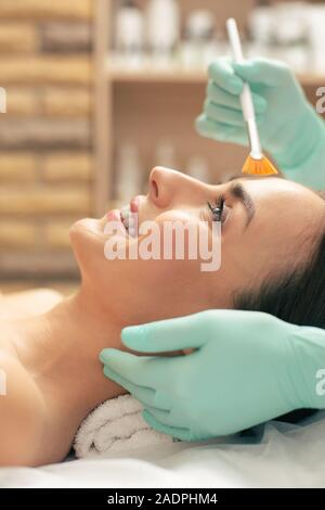 Close up photo of the beautician using the brush on the face of woman Stock Photo