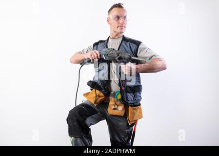 Builder with a drill in his hands, in unloading, aims to the right. Stock Photo