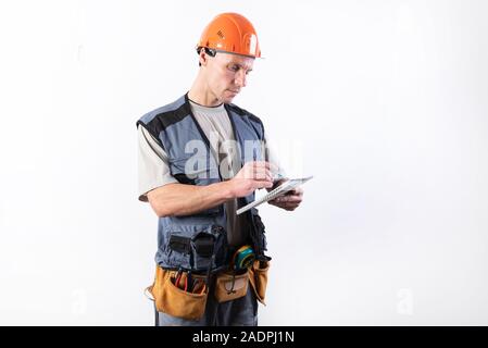 Builder with a notepad. In a helmet and a robe. Writes data. Stock Photo