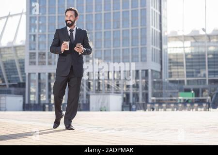 Joyful smiling businessman standing in the urban settings Stock Photo