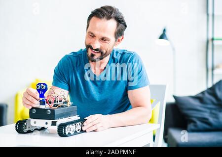 Cheerful bearded man testing his robotic device at home Stock Photo