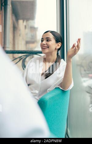Cheerful woman sitting on the balcony and smiling while talking Stock Photo