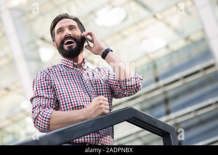 Low angle of a pleasant smiling man having a phone conversation Stock Photo