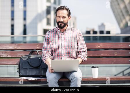 Pleasant adult man using his laptop outdoors Stock Photo