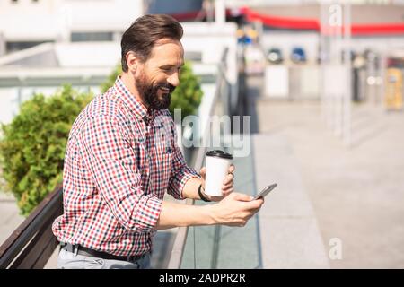 Joyful handsoem man using his smartphone outdoors Stock Photo