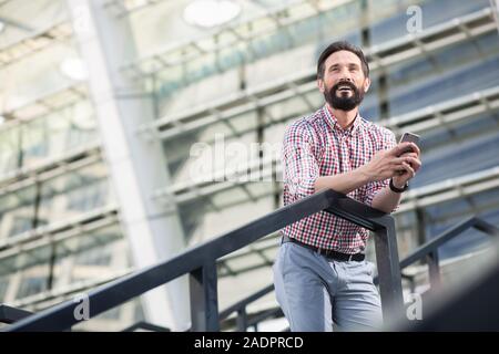 Low angle of a positive man using his mobile phone Stock Photo