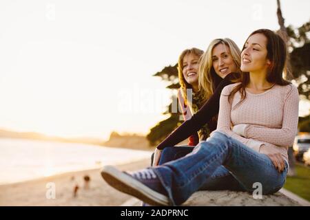 Three friends sitting together at the beach Stock Photo