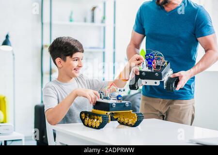 Cheerful smart schoolboy experimenting with robotic devices Stock Photo