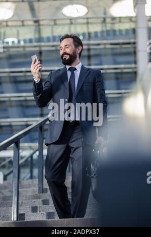 Optimistic handsome businessman walking down the stairs outdoors Stock Photo