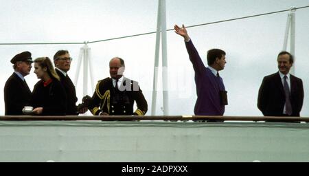 AJAXNETPHOTO. JULY,1991. MILFORD HAVEN, WALES, UK. - ROYAL WAVER - HRH DUKE OF YORK (2ND FROM RIGHT.) WAVES TO CREWS OF TALLS OF SHIPS DURING PARADE OF SAIL FROM DECK OF HMRY BRITANNIA.  PHOTO:JONATHAN EASTLAND/AJAX  REF;CD:215014 117 Stock Photo