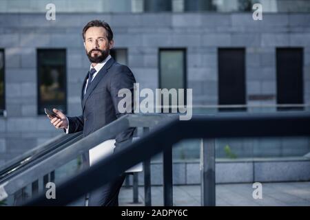 Serious businessman using his phone while looking at you Stock Photo