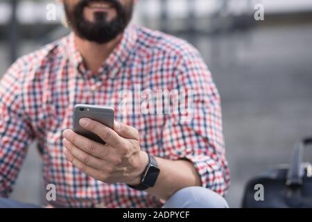 Smiling adult man using his phone outdoors Stock Photo