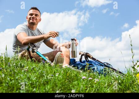 Low angle of a delighted man with prosthesis sitting on the grass Stock Photo