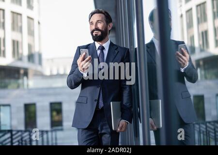 Optimistic handsome businessman using his smartphone with pleasure Stock Photo