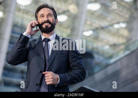 Waist up of a smiling handsome businessman having a phone conversation Stock Photo