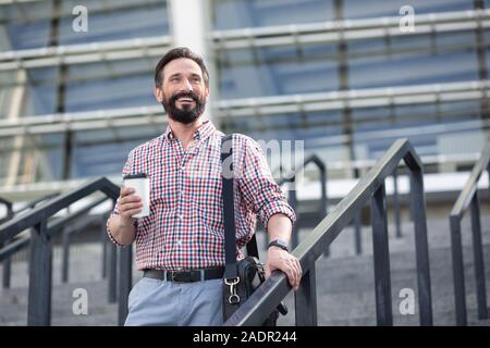 Optimistic handsome man walking down the stairs Stock Photo