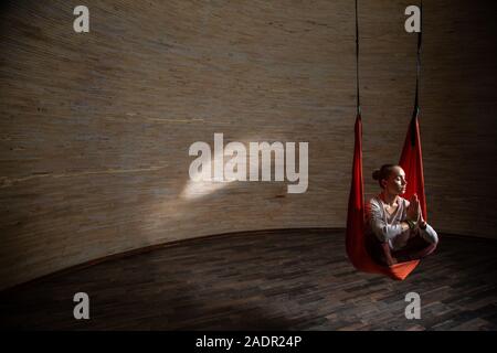 Full length of peaceful woman practicing meditation in aerial yoga Stock Photo