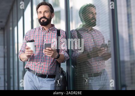 Pleasant smiling man leaning on the glass of office building Stock Photo