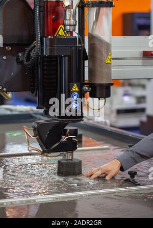 Industry worker operating CNC abrasive water jet cutting machine Stock Photo