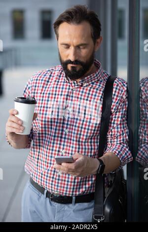 Concentrated bearded man using his mobile phone Stock Photo