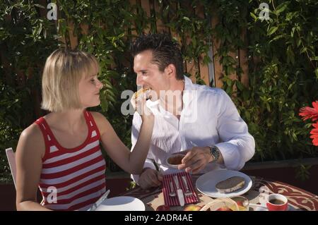 Junges Paar frühstückt im Freien - Young couple having breakfast outdoors Stock Photo