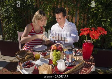 Junges Paar frühstückt im Freien - Young couple having breakfast outdoors Stock Photo