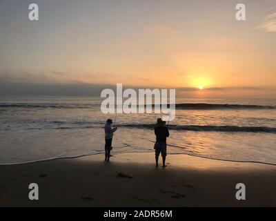 Men surf fishing from a beach in Malibu at sunset in Los Angeles, CA Stock Photo