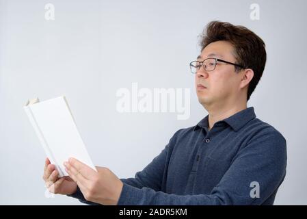 Asian male trying to read something in his book. poor sight, presbyopia, myopia. Stock Photo