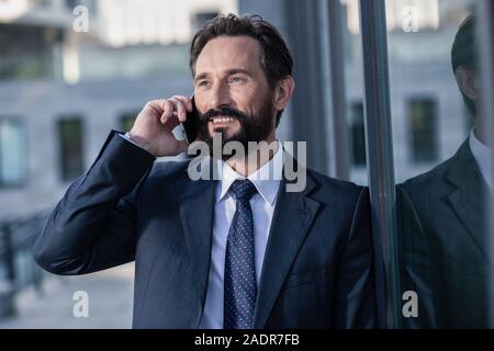 Cheerful bearded businessman talking on a phone Stock Photo